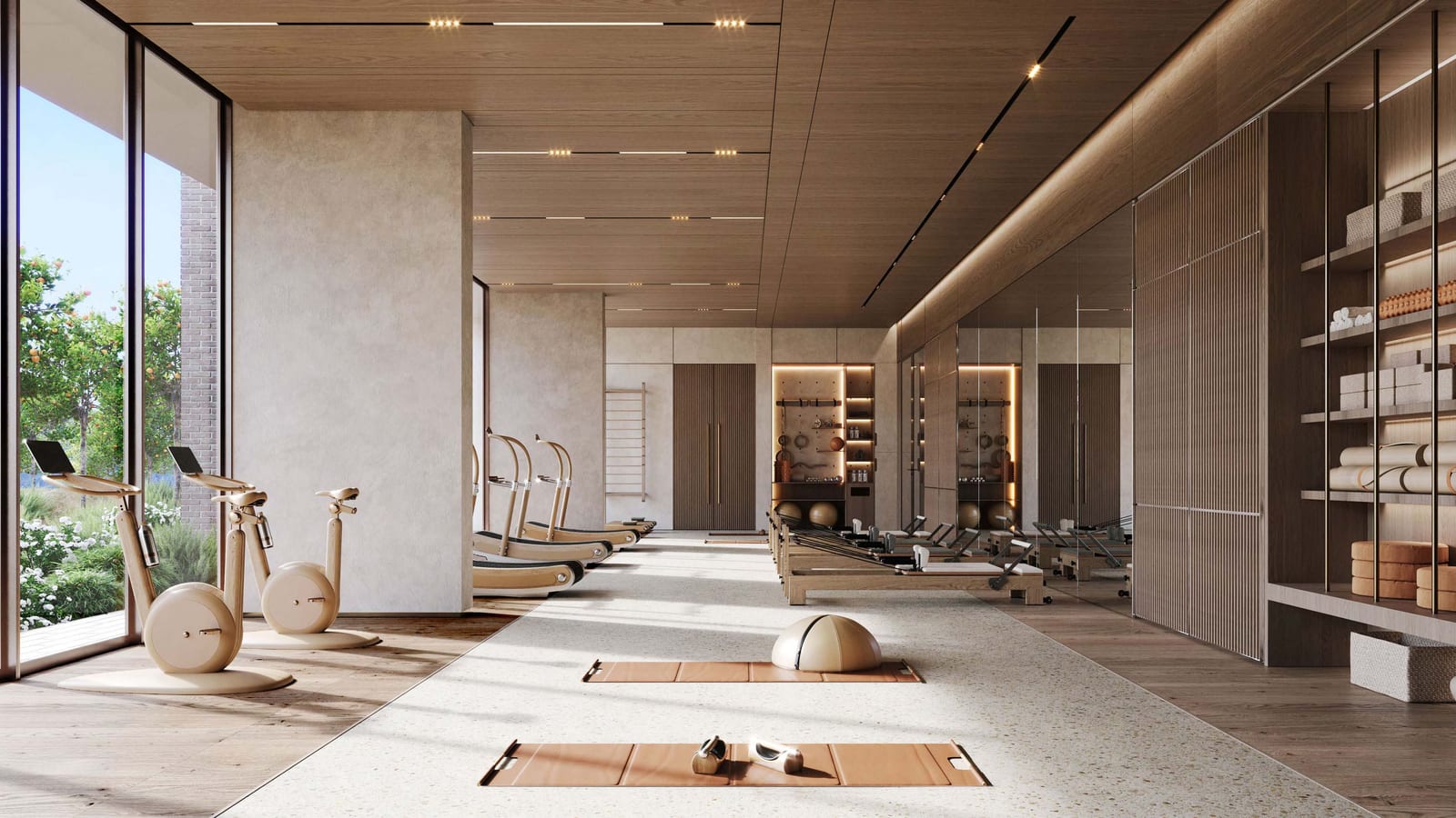 Gym with exercise bikes, treadmills and reformer beds beside full-height garden windows