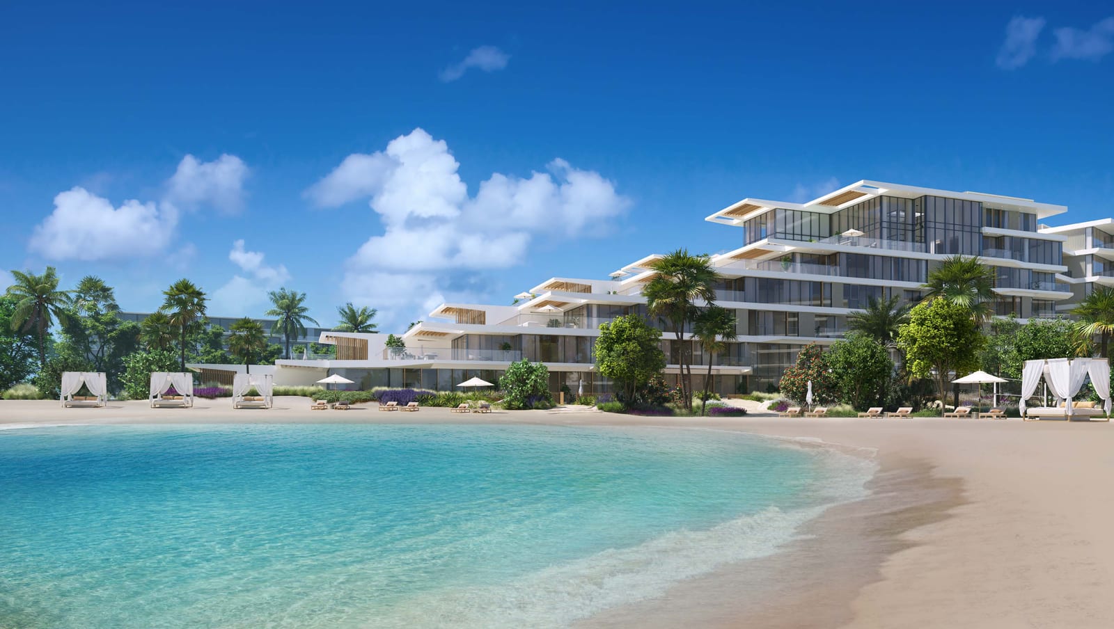 Stepped white building with cabanas on a sandy beach and shallow turquoise water in the foreground